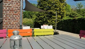 Un espace extérieur aménagé avec des sièges, un mur en briques, une table et des bancs aux couleurs vives.