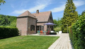 Une maison en briques avec un patio, une table et des chaises, et un chemin.