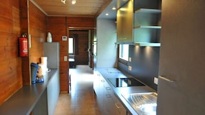 A modern kitchen with wooden walls, stainless steel appliances, and a central island. - Holiday Home in Houyet With Sauna & Garden (Houyet)