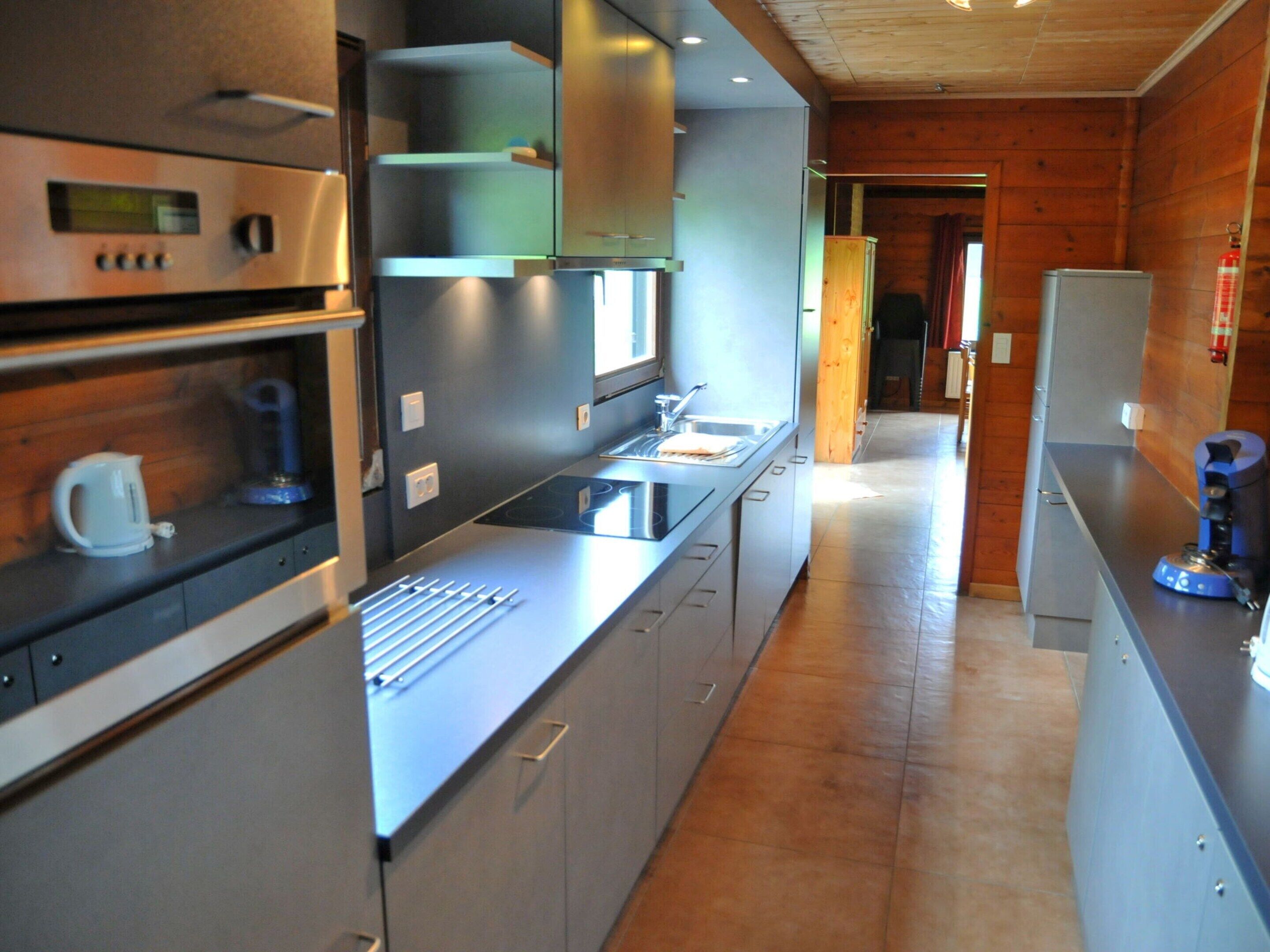 A modern kitchen with stainless steel appliances, a built-in oven, and a long countertop.