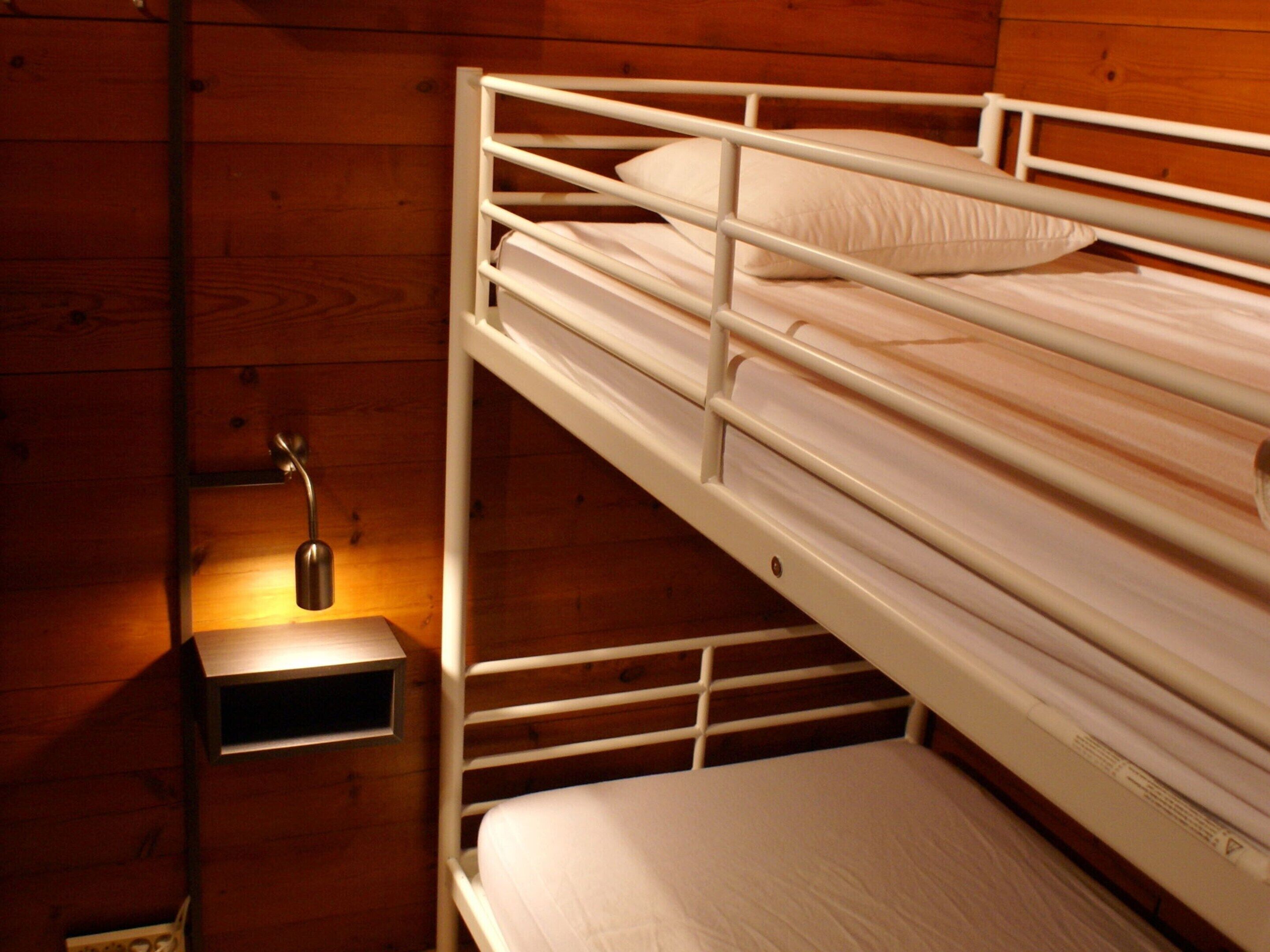 Una cama litera con una mesita de noche pequeña y una lámpara.