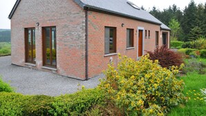 A modern brick house with a sloped roof, large windows, and a well-maintained garden with yellow flowers. - Bungalow in Peaceful Environment (Rochefort)