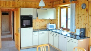 A wooden cabin kitchen with a stove, microwave, sink, and wooden cabinets. - Bungalow in Peaceful Environment (Rochefort)