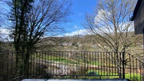 A balcony with a metal railing overlooking a residential area with houses and trees. - Cozy Holiday Home in Durbuy With Garden (Durbuy)