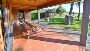 A covered patio area with wooden benches and a stone-tiled floor. - Holiday Home in Durbuy With Garden & BBQ (Durbuy)