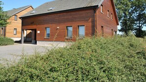 A wooden house with a sloped roof and a chimney, surrounded by dense greenery. - Holiday Home in Durbuy With Garden & BBQ (Durbuy)
