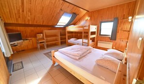 A cozy attic bedroom with a bunk bed, a single bed, a TV, and a window. - Holiday Home in Durbuy With Garden & BBQ (Durbuy)