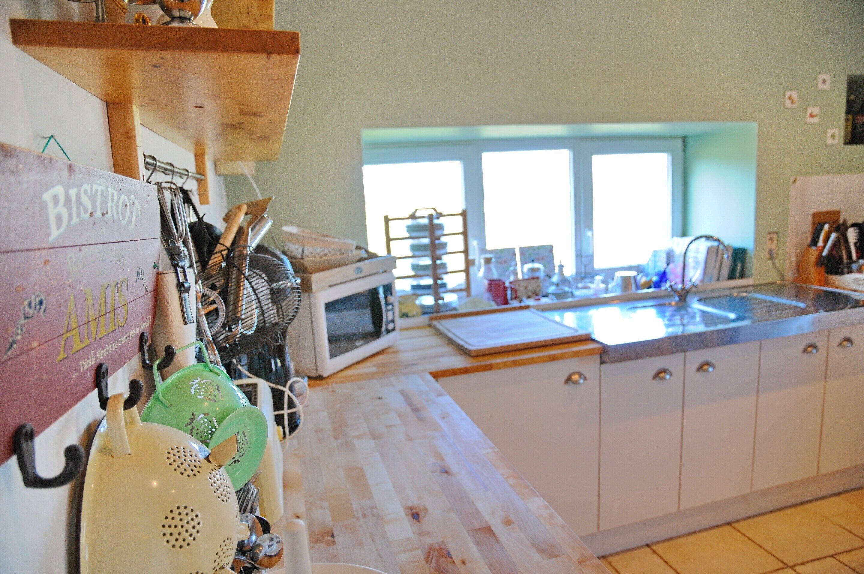 A kitchen with white cabinets, a microwave, a sink, and various utensils.