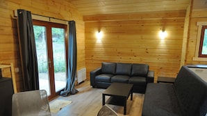 A wooden cabin interior with a sofa, chairs, and a table. - Chalet in Oignies With BBQ and Terrace (Viroinval)