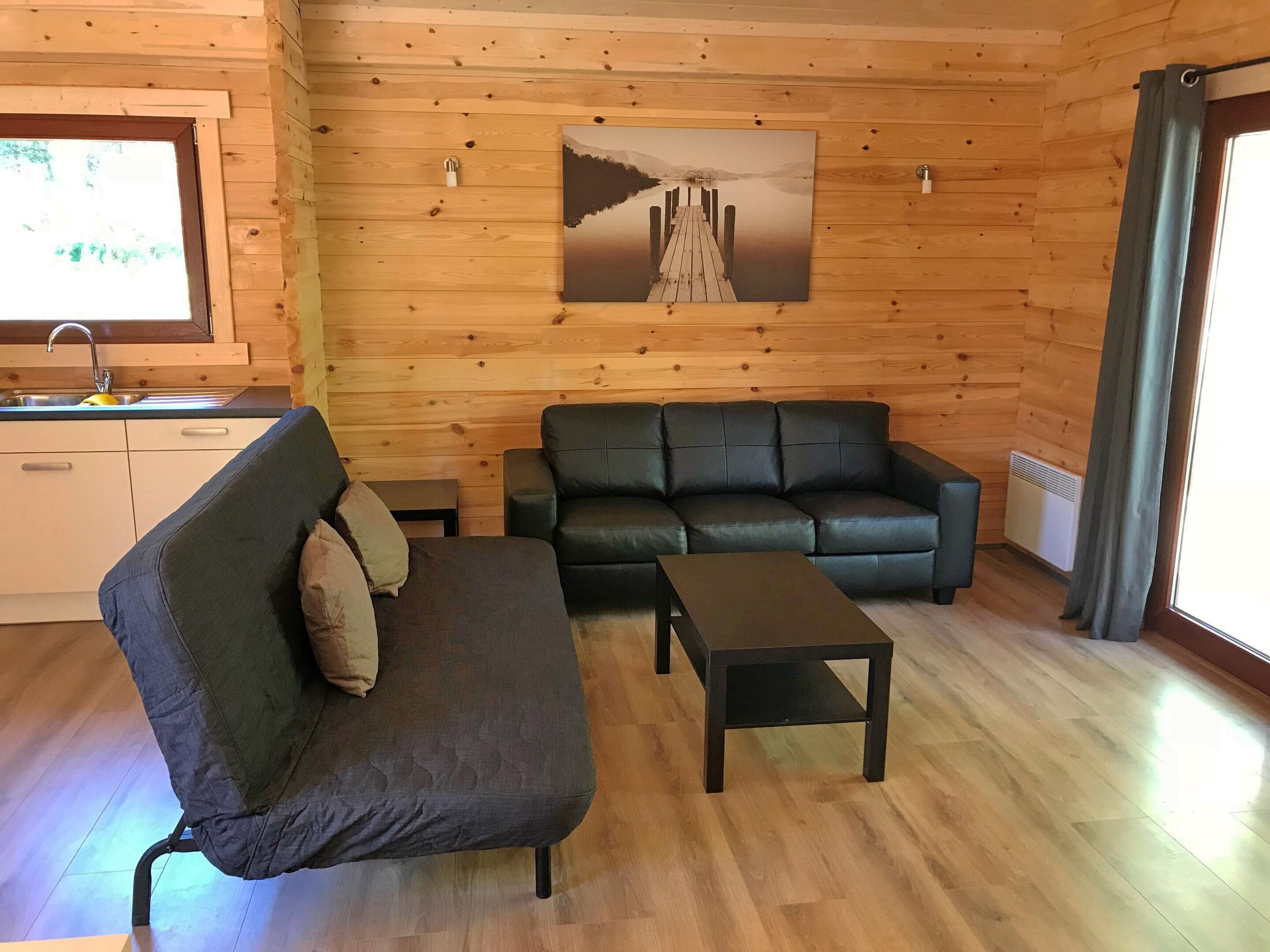 A wooden interior with a sofa, a small table, and a painting on the wall.