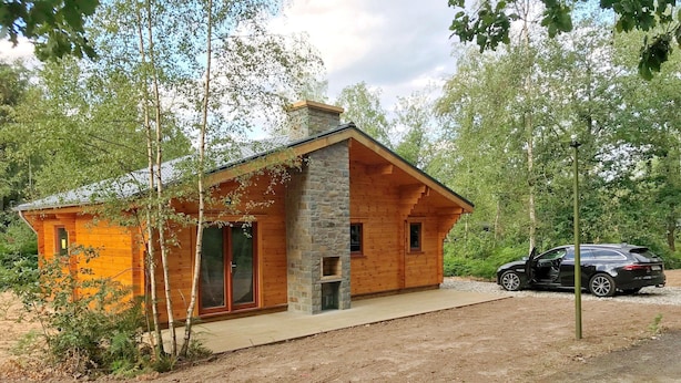 A rustic cabin with a stone chimney, wooden walls, and a car parked outside. - Chalet in Oignies With BBQ and Terrace (Viroinval)