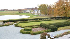 A landscaped garden with a pond, neatly trimmed hedges, and a building in the background. - Castle in Ardennes Near Forest & Sauna (Libramont-Chevigny)