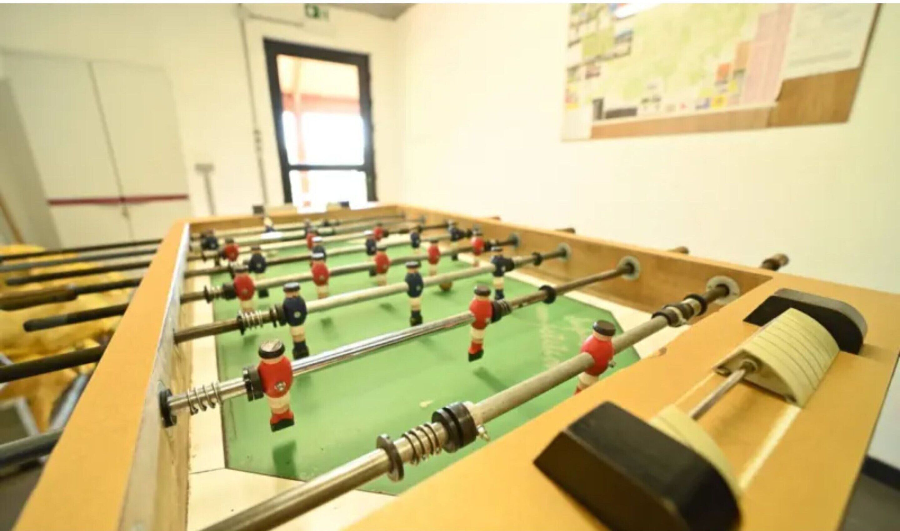 A foosball table in a room with a window and a bulletin board on the wall.