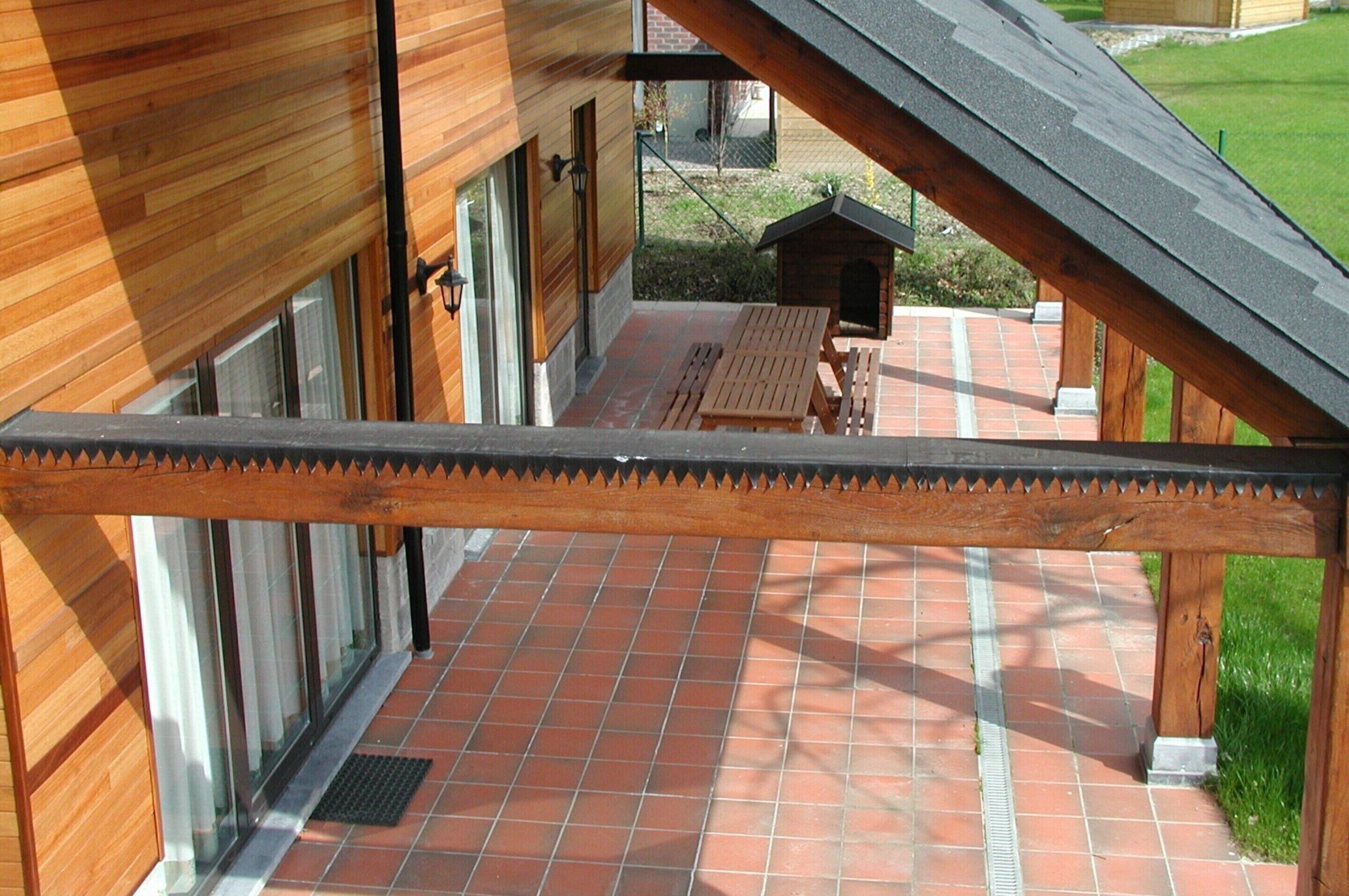 Exterior de madera con un patio de baldosas, una terraza de madera y un pequeño canil.