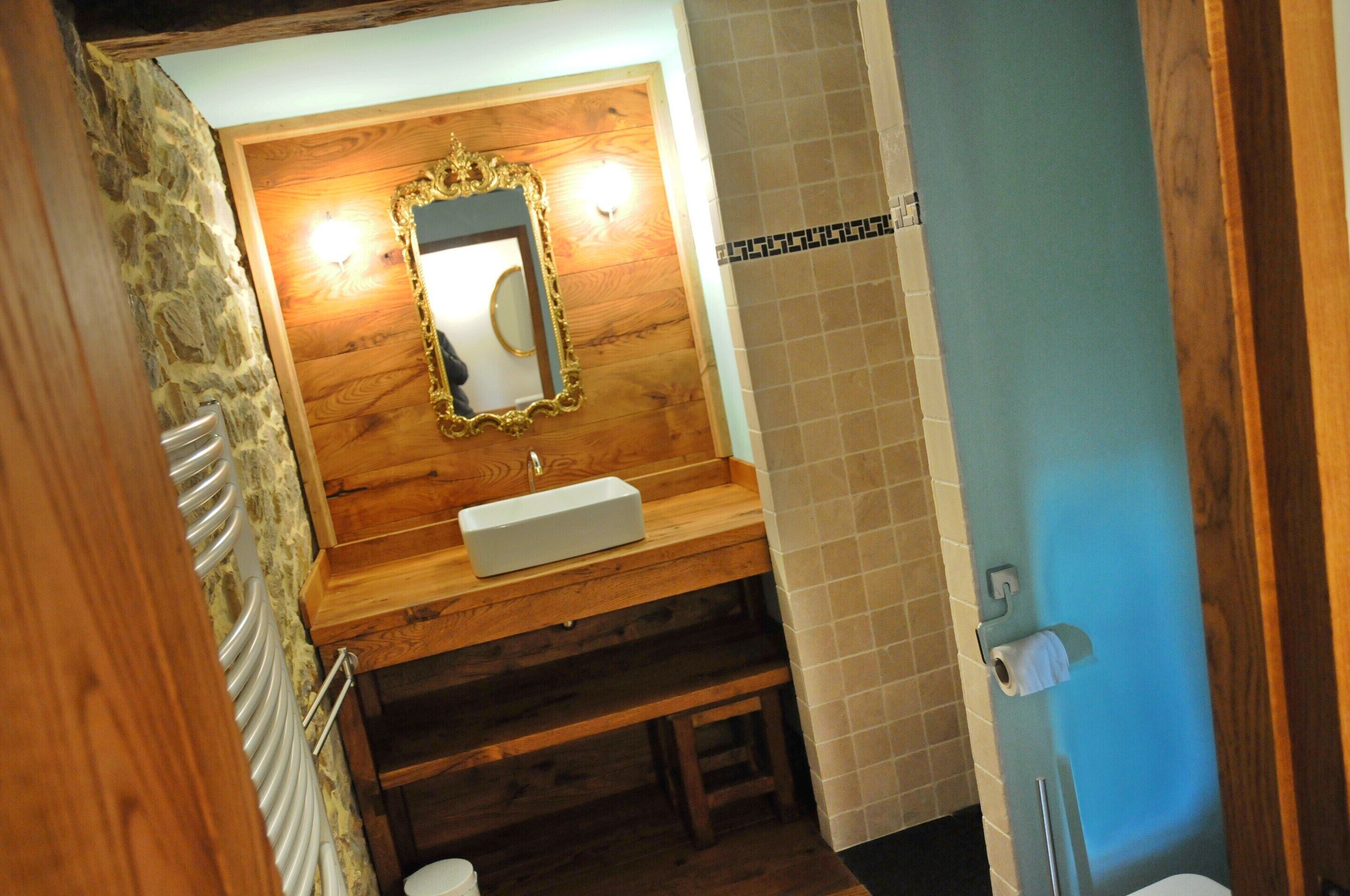 A bathroom with a wooden vanity, a mirror, a sink, and a toilet.
