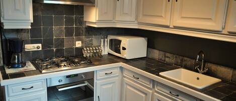 A kitchen with white cabinets, a microwave, a sink, and a stove.