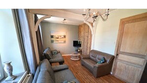 A living room with a sofa, armchairs, a TV, and a wooden floor. - Holiday Home in Hotton Near Caves of Hotton (Hotton)