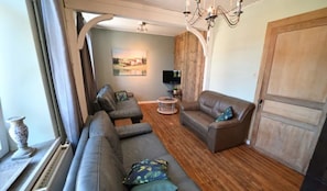 A living room with a sofa, armchairs, a TV, and a wooden floor. - Holiday Home in Hotton Near Caves of Hotton (Hotton)