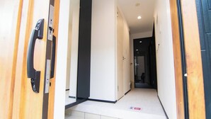 A hallway with a wooden door, a black door frame, and a tiled floor. - Convertel Honhaneda by Tranova (Tokyo)