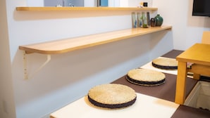 A room with a wooden shelf, a table, and three woven placemats. - Convertel Honhaneda by Tranova (Tokyo)