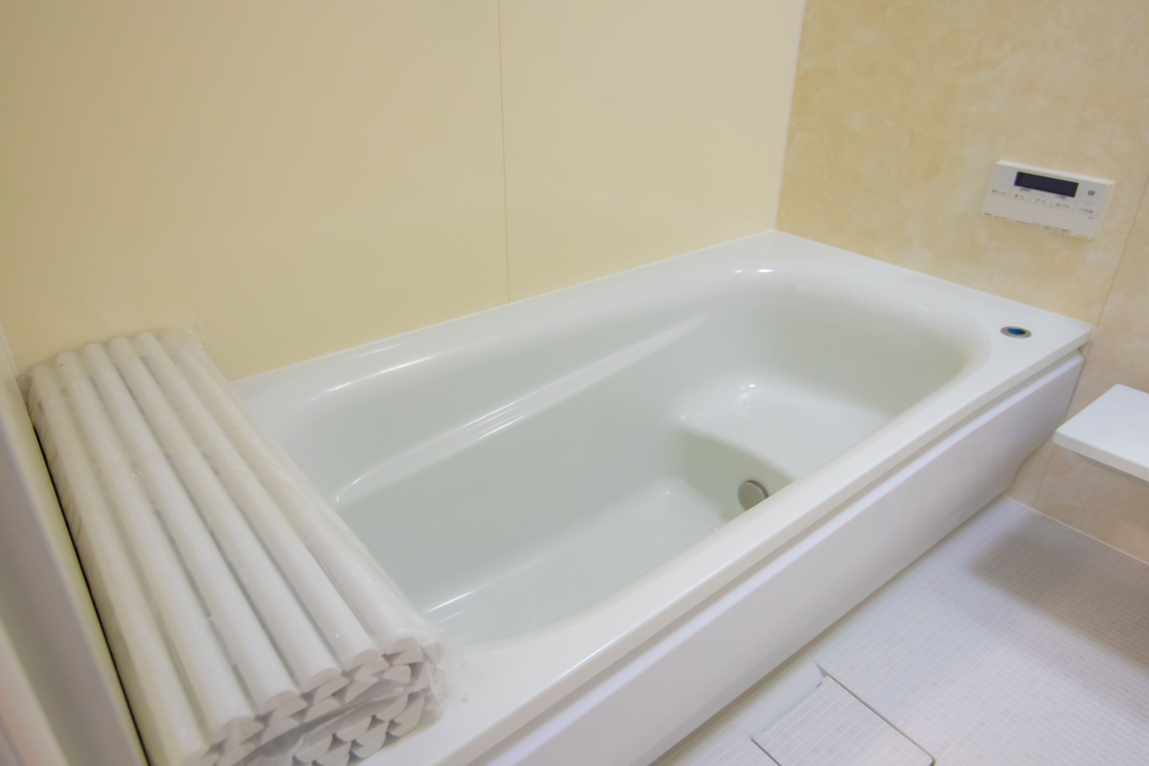 A white bathtub with a control panel on the wall.