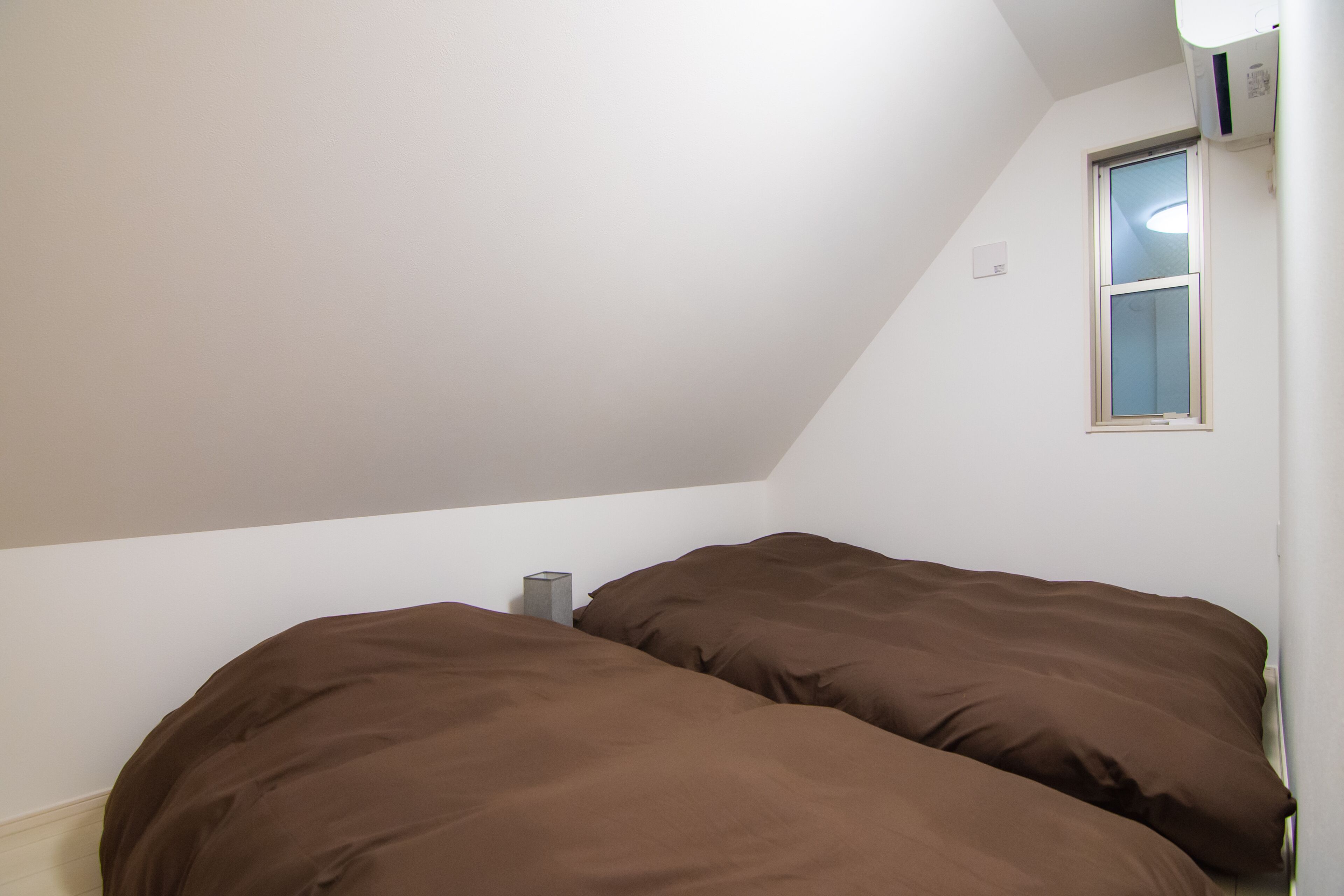 A small, dimly lit room with a sloped ceiling and a single window.
