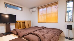 A bedroom with a bed, a TV, a window with blinds, and an air conditioning unit. - Convertel Honhaneda by Tranova (Tokyo)