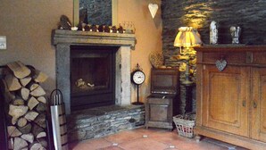 Una habitación acogedora con chimenea de piedra, un reloj y un aparador de madera.