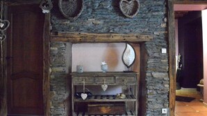 Una chimenea de piedra rústica con una repisa de madera, un espejo y un estante con objetos decorativos.