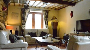 Una sala de estar acogedora con chimenea, sofás de cuero, una mesa de centro y televisión.