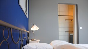 A hotel room with a bed, a nightstand, a lamp, and a bathroom visible through an open door. - Holiday Home in Durbuy With Garden & BBQ (Durbuy)