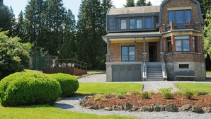 A two-story house with a balcony, a garage, and a well-maintained garden. - Holiday Home in Durbuy With Garden & BBQ (Durbuy)
