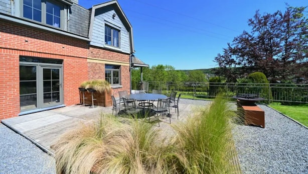 A two-story house with a patio, a dining table, and chairs. - Holiday Home in Durbuy With Garden & BBQ (Durbuy)