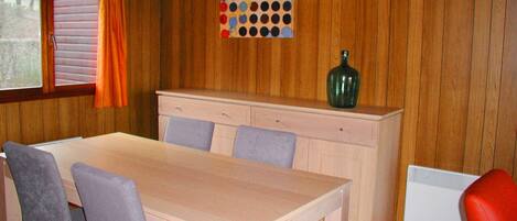 Un comedor con mesa de madera, sillas, un armario y una lámpara fijada a la pared.