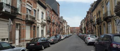 Una calle bordeada de automóviles estacionados y edificios de ladrillo tradicionales con varios pisos y balcones.