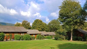 Eine Reihe von blockhausartigen Gebäuden mit einer grünen Wiese und Bäumen im Hintergrund.