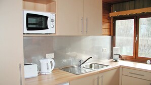 Eine Küche mit Mikrowelle, Toaster, Wasserkocher, Spüle und einem Fenster mit Blick auf Bäume.