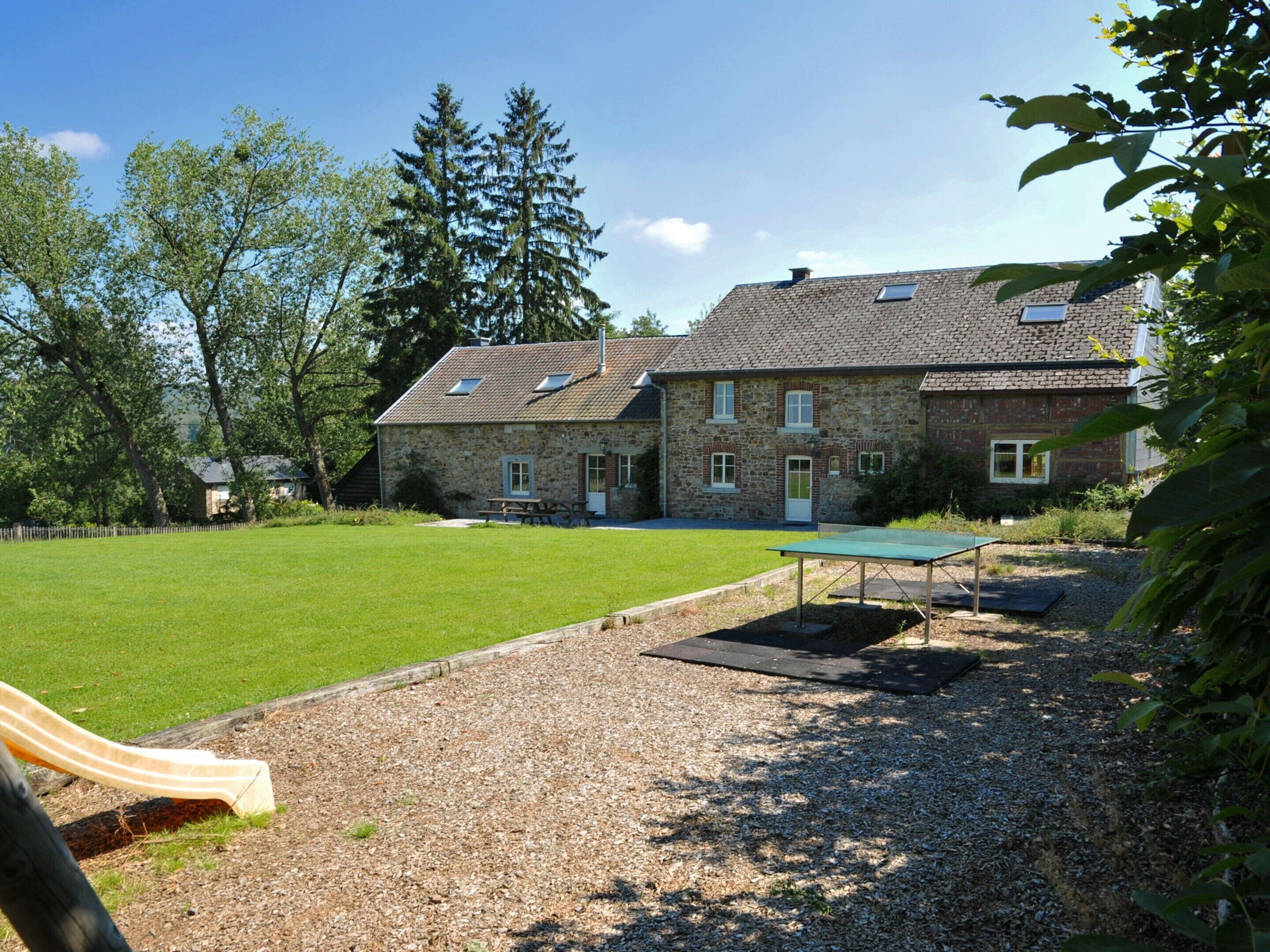 A stone building with a grassy yard, a picnic table, and a ping pong table.