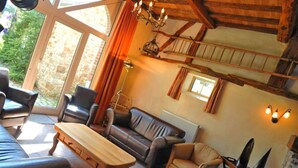 Ein gemütliches Wohnzimmer mit Holztisch, Ledersofas und einer Steinwand.