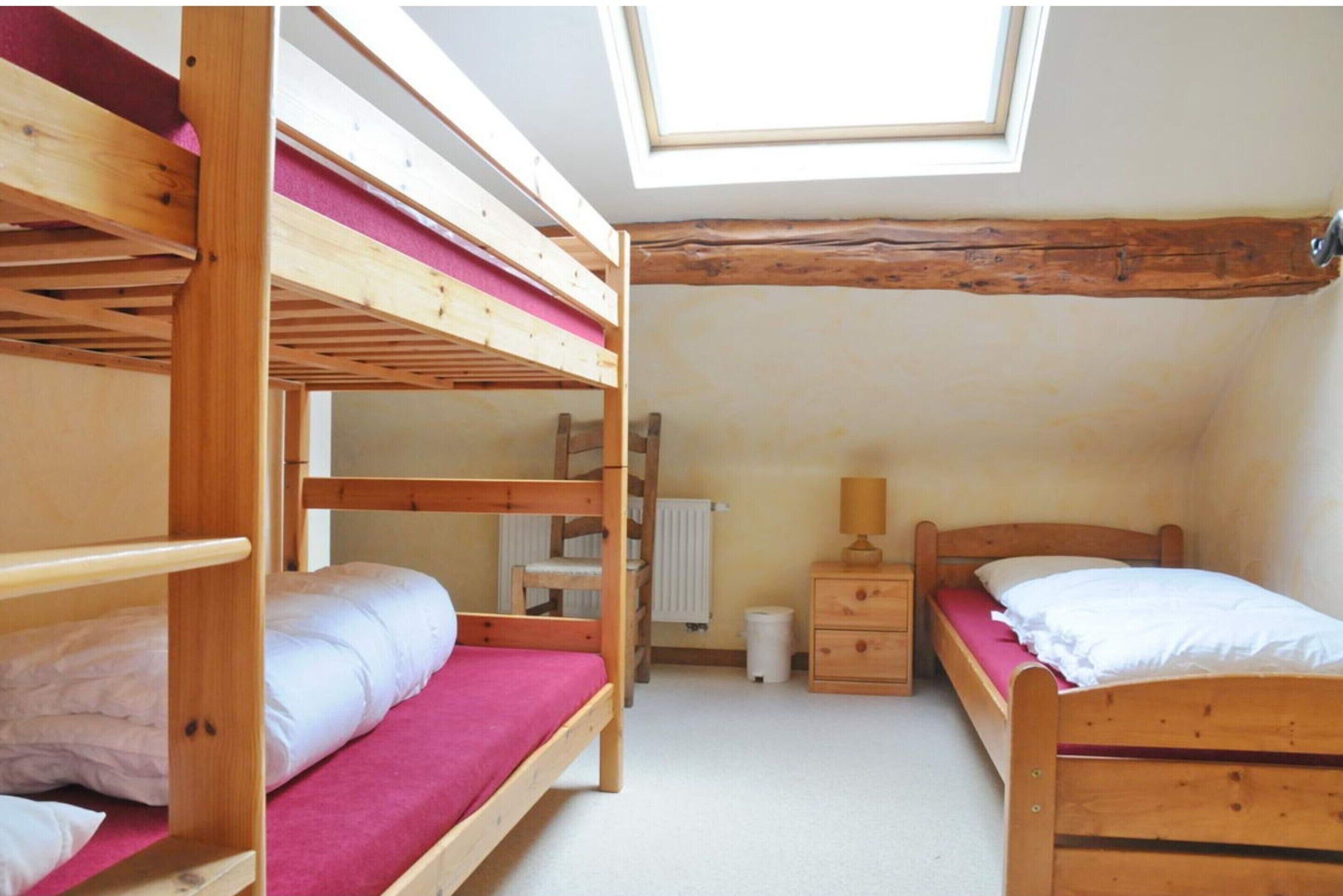 A dormitory room with bunk beds, a skylight, a radiator, and a small wooden dresser.
