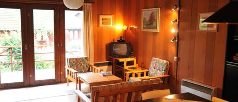 A cozy room with wooden walls, a television, a table with a floral tablecloth, and a bench.