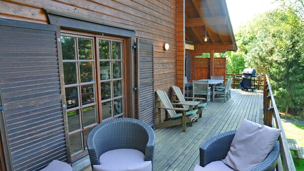 A wooden deck with wicker furniture, a table, and chairs. - Holiday Home in Durbuy With Garden (Durbuy)