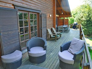 Une terrasse en bois avec des meubles en osier, une table et des chaises.