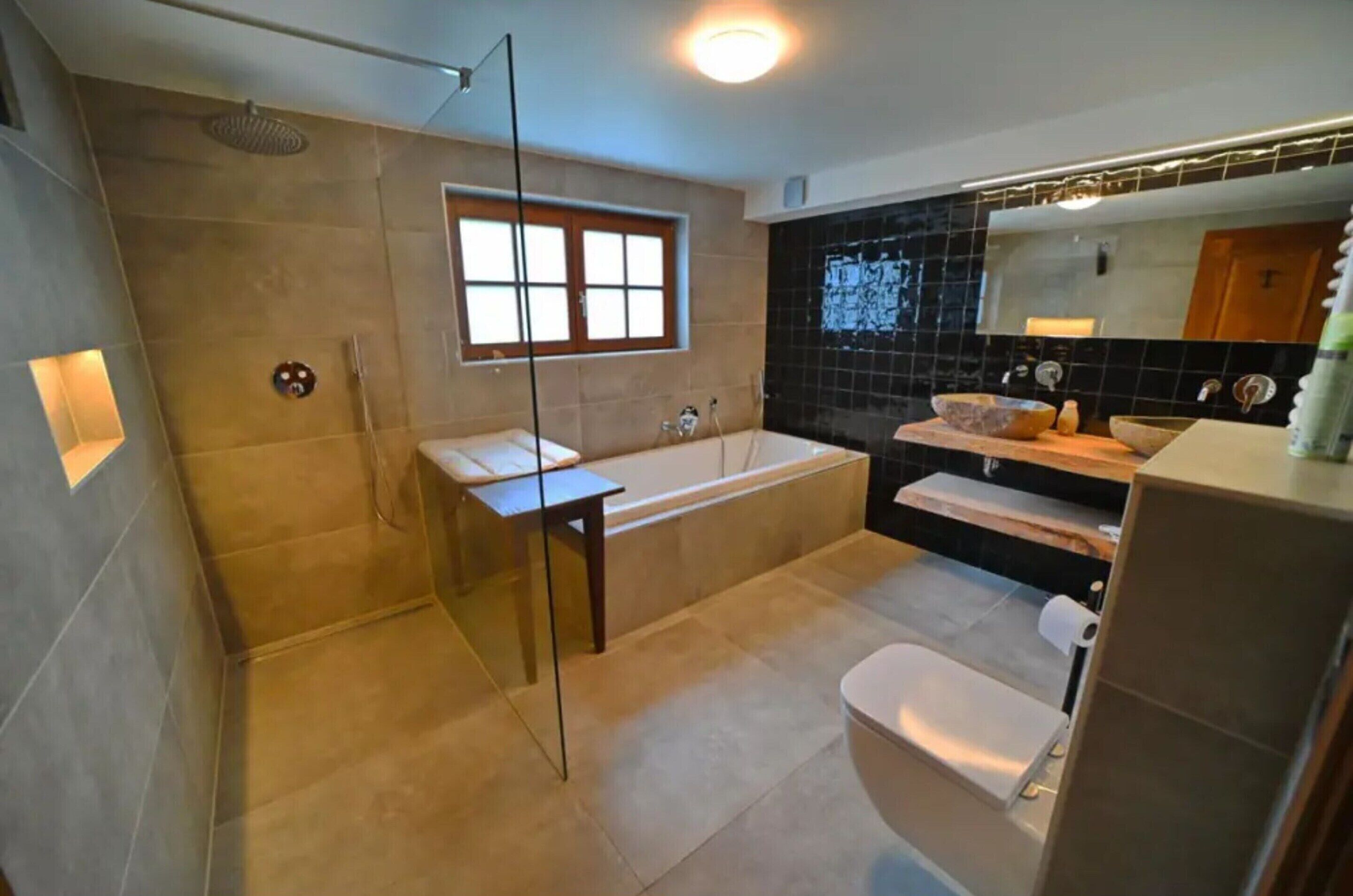 Une salle de bain moderne dotée d’une douche à parois de verre, d’une baignoire sur pieds et d’un meuble-lavabo avec un grand miroir.