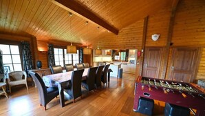 A wooden-floored dining area with a foosball table, leather chairs, and a kitchen in the background. - Holiday Home in Durbuy With Garden (Durbuy)