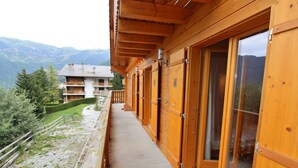 Ein Holzbalkon mit Schiebetüren, mit Blick auf eine gebirgige Landschaft.