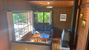 A room with a sofa, a coffee table, a heater, and large windows with curtains. - Ortho Hideaway With Garden (La Roche-en-Ardenne)