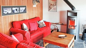 A cozy living room with a red sofa, a wooden table, a fireplace, and a mounted deer head. - Chalet for 6 People With Views of Veysonnaz (Veysonnaz)