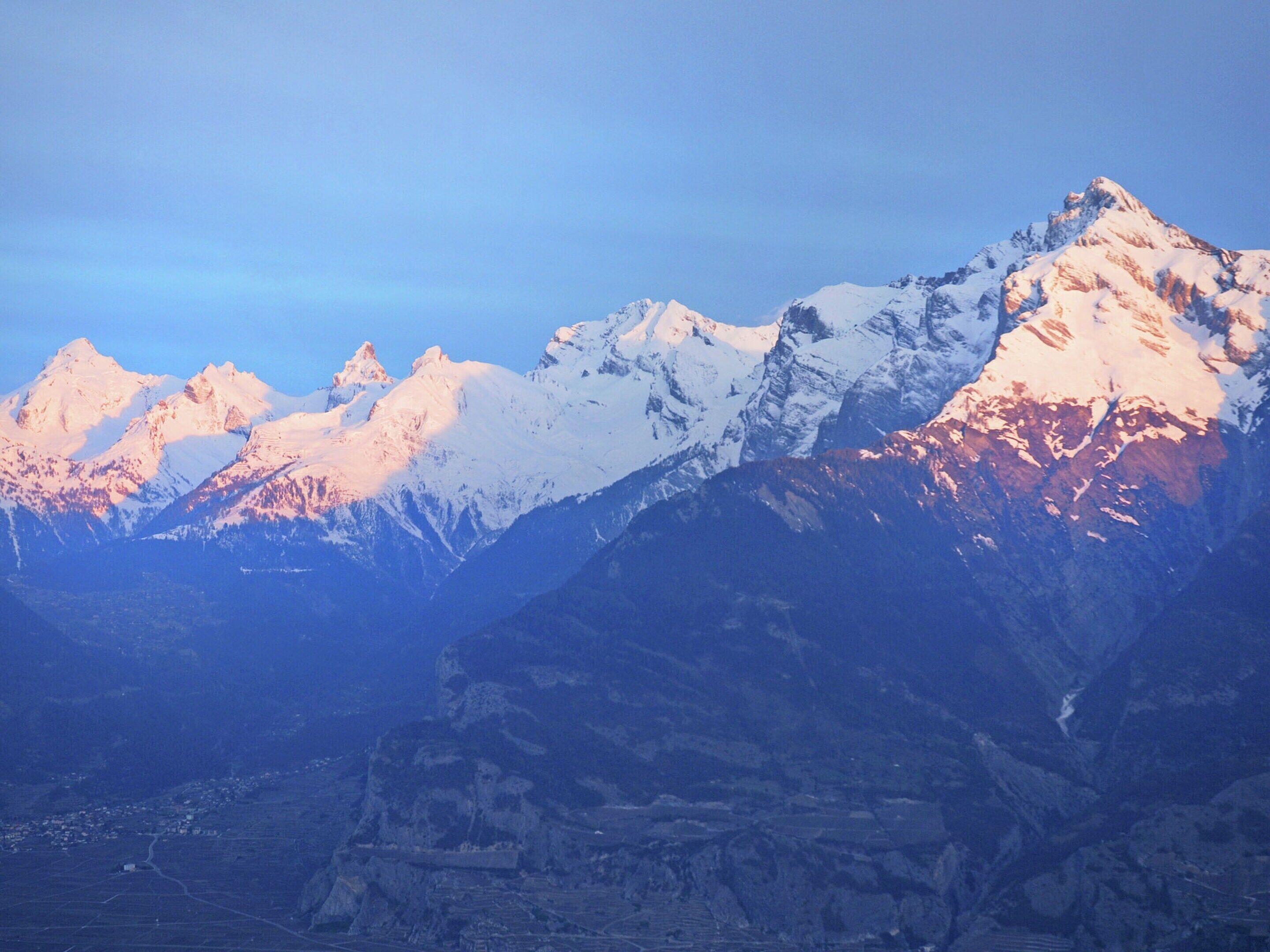 A mountain range with snow-covered peaks and a valley below.