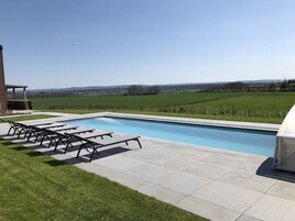 A rectangular swimming pool with a clear blue water surface, surrounded by a paved deck.